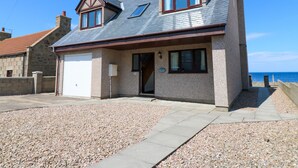 A two-story house with a garage, a small porch, and a view of the sea. - Shoreline House (Fraserburgh)
