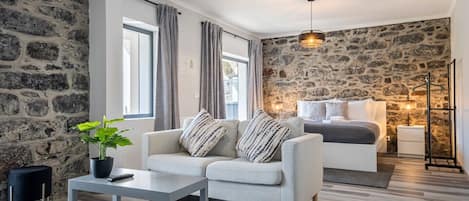 Una sala moderna con una pared de piedra, un conjunto de sofá, una mesita de centro y una mesita de noche con lámpara.