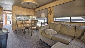 A compact kitchen with wooden cabinets, a dining table with chairs, and a window with a view.