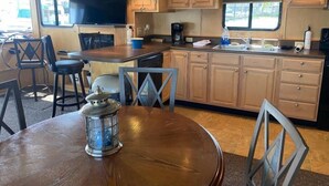 A compact kitchen with wooden cabinets, a central island, and a dining area with a round table and chairs.