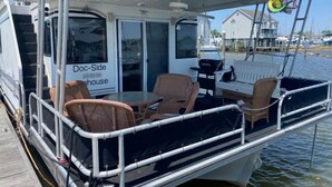 A boat with a covered deck area featuring wicker furniture and a table.