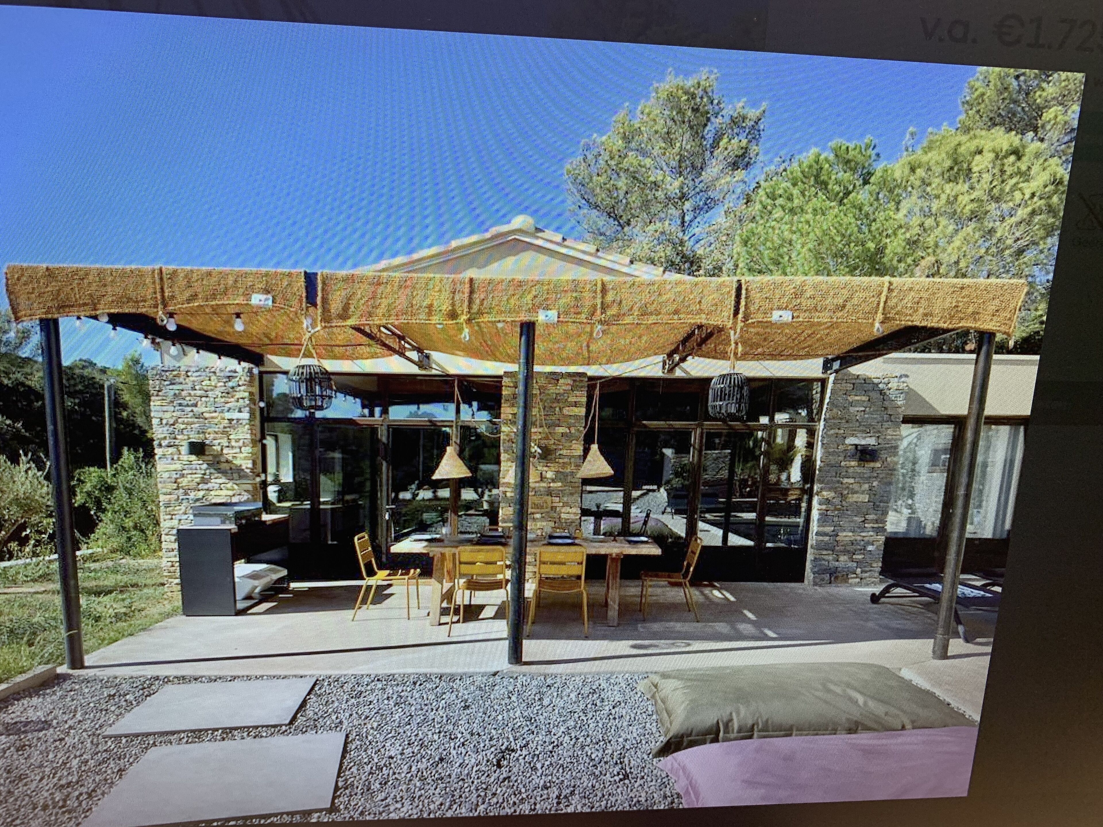 Un espace extérieur moderne, aménagé avec des murs en pierre, un patio couvert et une cheminée en pierre.