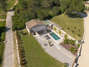 An aerial view of a house with a swimming pool, a covered patio, and a fenced yard.