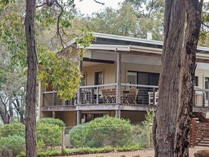 Un bâtiment à deux étages doté d’un balcon, d’un espace extérieur aménagé pour s’asseoir et d’un jardin clos.