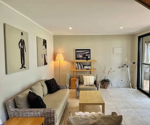 A living room with a sofa, armchair, coffee table, and a telescope.