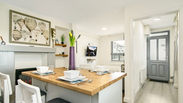 Una cocina moderna con una isla de madera, sillas blancas y una chimenea.