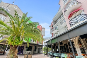 Une cour avec un palmier, des sièges en plein air et un bâtiment doté de balcons et d’une enseigne.