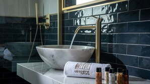 Une salle de bain dotée d’un grand lavabo en marbre, d’un robinet doré et d’une serviette portant le nom de l’hôtel.