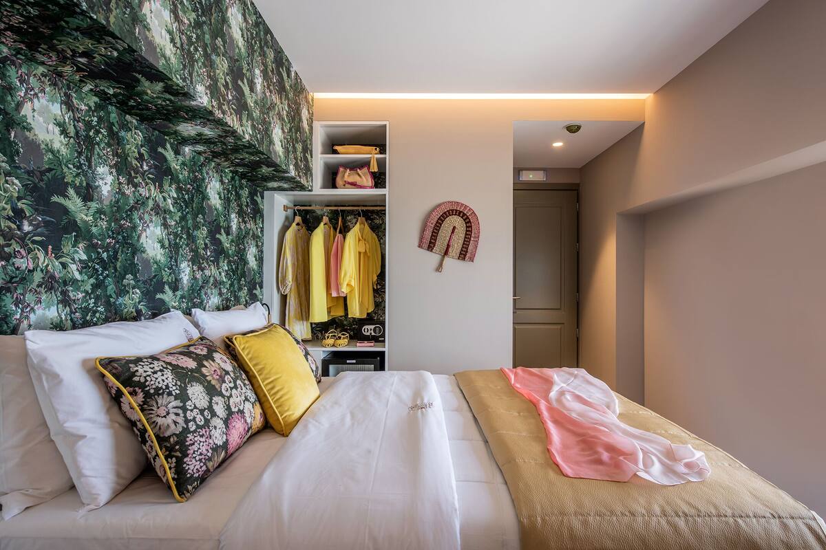 A bedroom with a bed, a wardrobe, and a closet with hanging clothes.