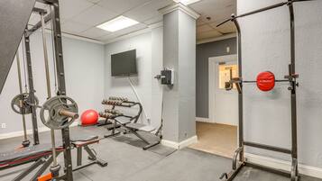 A gym with weightlifting equipment, a television, and a red exercise ball.