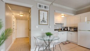 A modern kitchen with white cabinets, a glass dining table, and a framed picture of the Eiffel Tower. - Downtown Jacksonville Studio w/ City Views! (Jacksonville)