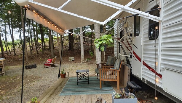A covered deck with a wooden bench, a small table, and potted plants. - Get away and get back to nature! (East Nassau)