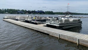 Un quai où sont amarrés plusieurs bateaux, une zone abritée et un kiosque en arrière-plan.