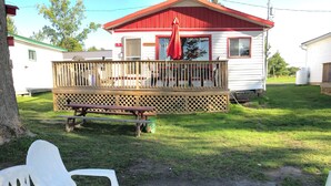 Une cabane dotée d’une terrasse en bois, d’une table de pique-nique et de sièges d’extérieur.