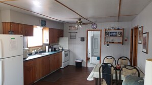 Une cuisine compacte dotée de meubles en bois, d’un réfrigérateur, d’un évier et d’un coin repas avec une table et des chaises.