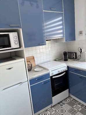 A kitchen with blue cabinets, a white microwave, a white stove, and a toaster.