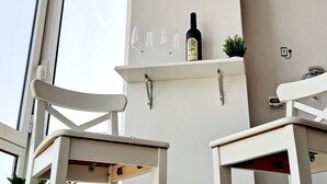 Une pièce avec un mur blanc, une bouteille de vin et deux verres à vin posés sur une étagère.