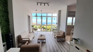 Un salon moderne doté d’une grande fenêtre donnant sur un paysage magnifique, et aménagé avec un canapé, des fauteuils et une table basse.
