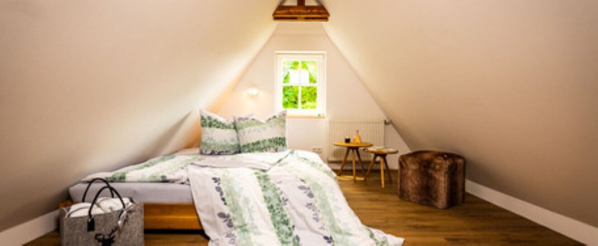 Ett mysigt sovrum på vinden med en säng, ett litet bord och en stol.