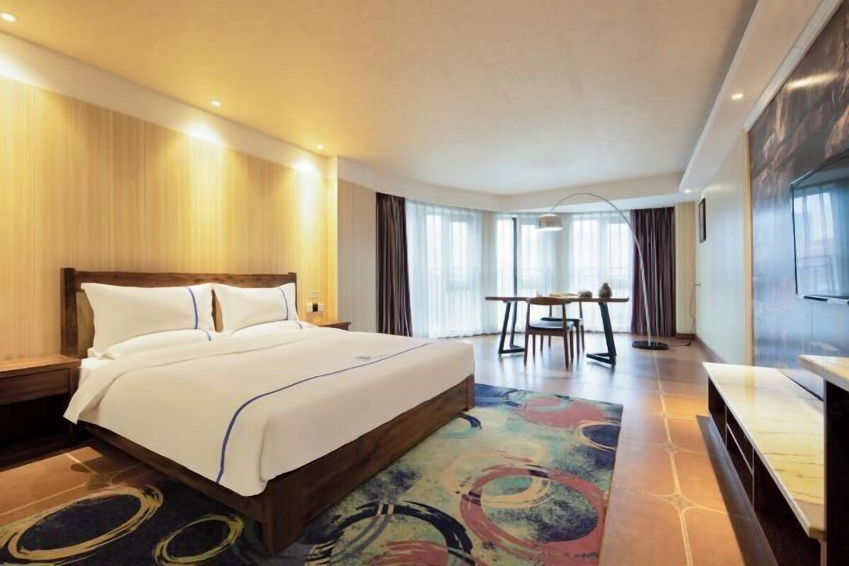 A hotel room with a large bed, a dining table, and a TV.