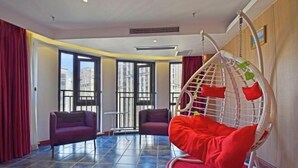 A modern room with a hanging chair, a sofa, and a view of buildings through large windows. - Chongqing Tianfei Art Hotel (Olympic Sports Center Yuanjiagang Subway Station) (Chongqing)