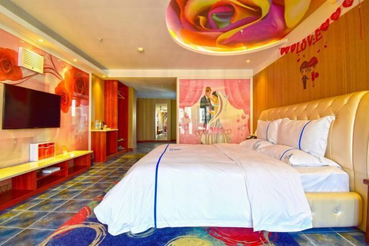 A hotel room with a large bed, a television, and a wall mural.