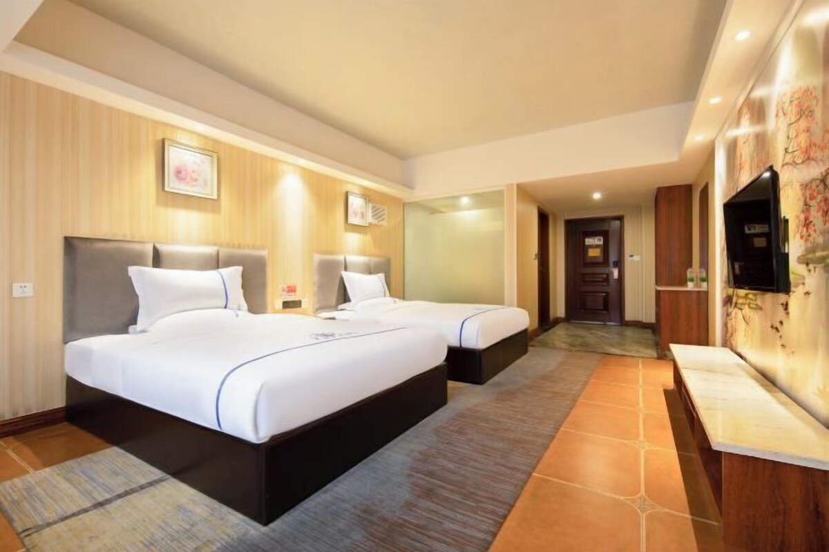 A hotel room with two beds, a TV, and a desk.