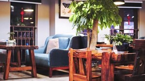 A cozy dining area with wooden furniture, a large potted plant, and pendant lighting. - Chongqing Tianfei Art Hotel (Olympic Sports Center Yuanjiagang Subway Station) (Chongqing)