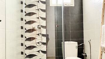 Un baño con cabina de ducha de vidrio, inodoro y lavabo.