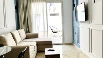 Una sala de estar moderna con un sofá color beige, una mesa de centro de madera y un televisor montado en la pared.