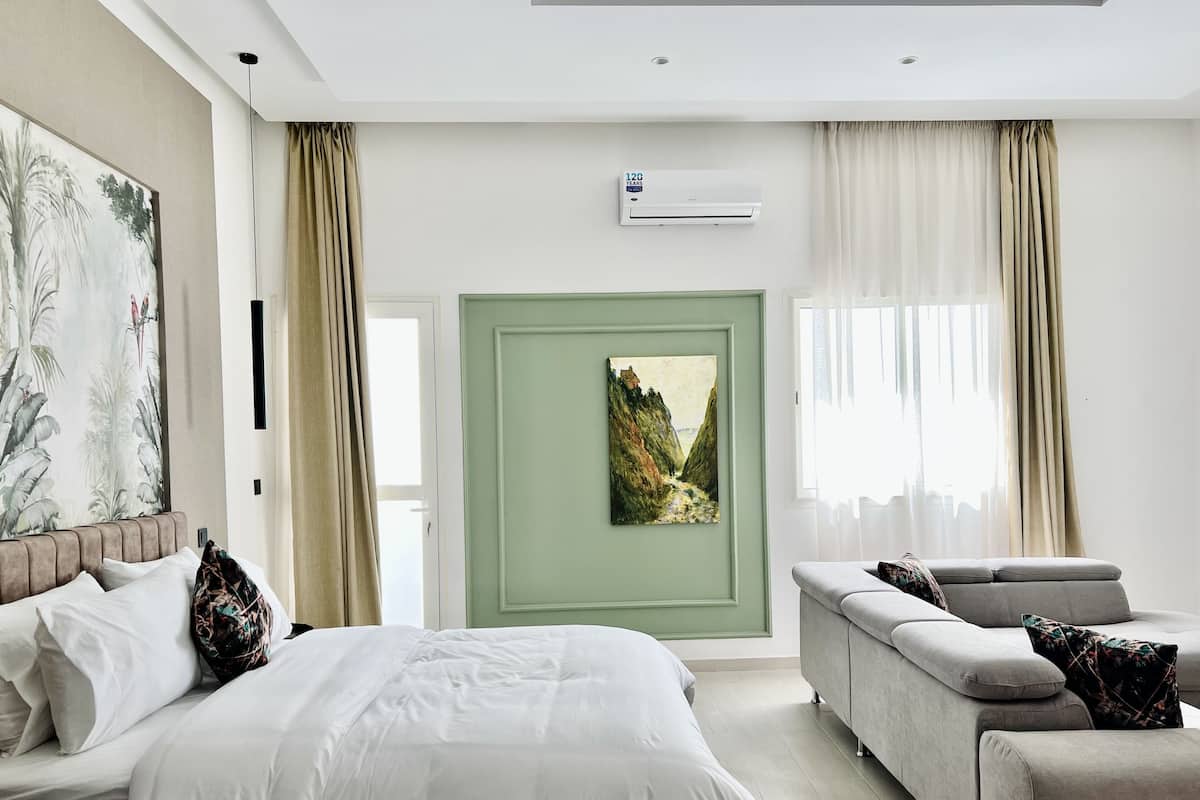 Una habitación de hotel moderna con una cama, un sofá, un cuadro y un equipo de aire acondicionado.
