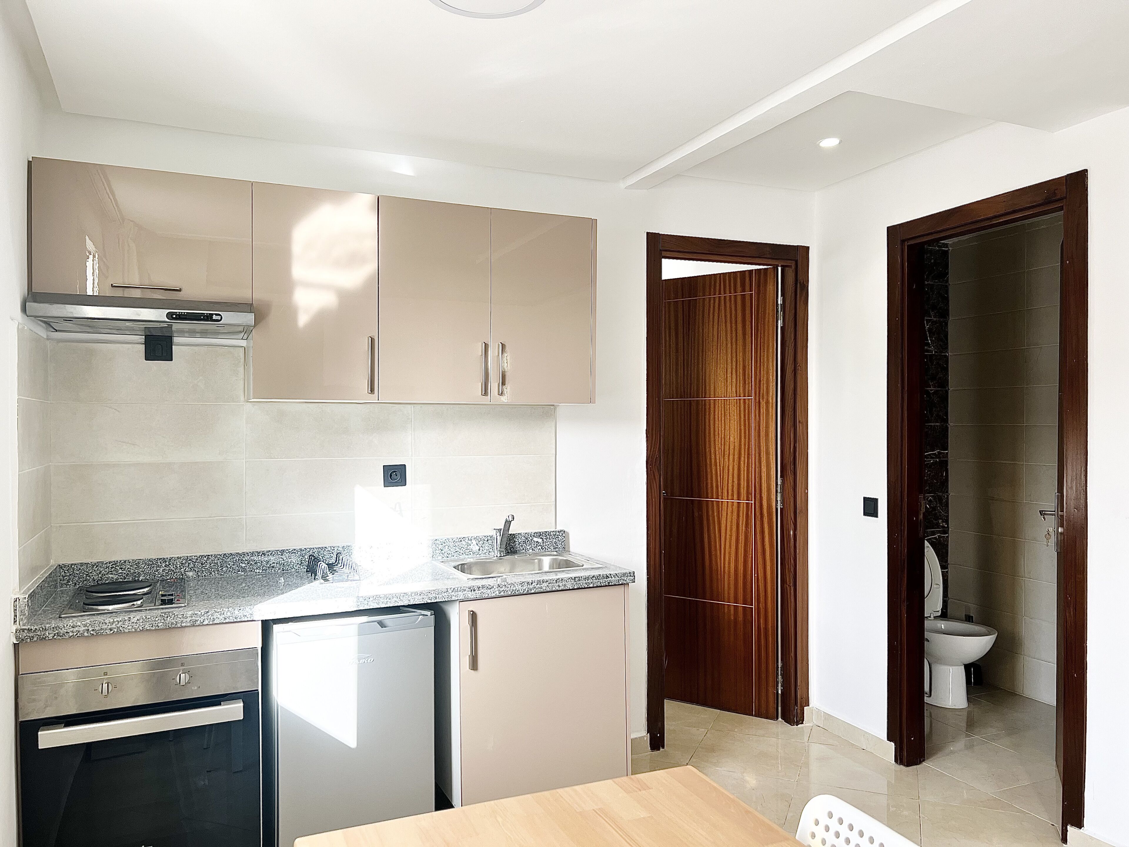 A modern kitchen with a built-in dishwasher, a sink, and wooden cabinets.