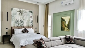 A modern hotel room with a large bed, a sofa, a green door, and two paintings. - MyCity (Rabat)
