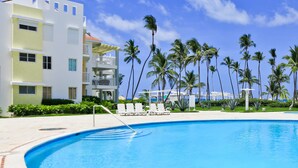 Ein modernes Hotel mit Swimmingpool, Palmen und blauem Himmel.