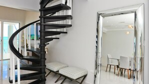 Ein modernes Interieur mit einer Wendeltreppe, einem großen Spiegel und einem Essbereich.