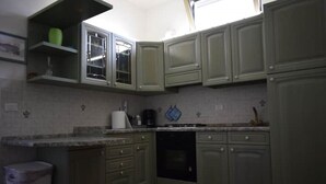 Cozinha com armários verde claro, bancada branca e lava-louças preta.