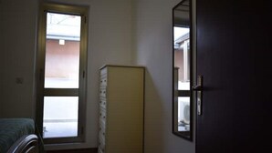 Um quarto com uma cama, cômoda, porta e janela.