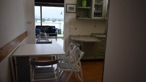 Uma sala de jantar com mesa e cadeiras, uma cozinha com armários e vista para o exterior.