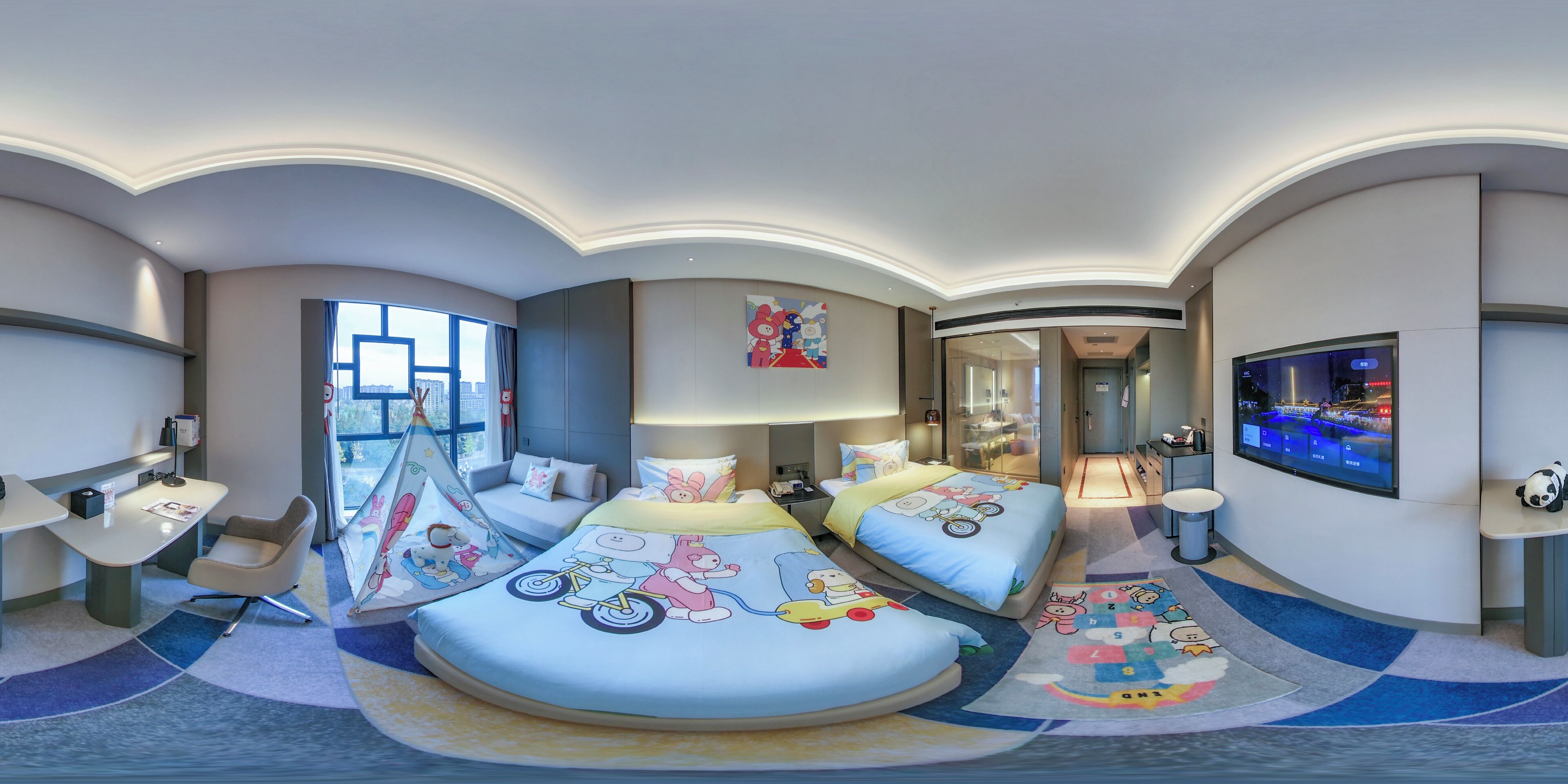 Una habitación de hotel con techo curvo, dos camas con ropa de cama de temática de dibujos animados, un escritorio, una silla, un televisor y un ventanal grande.