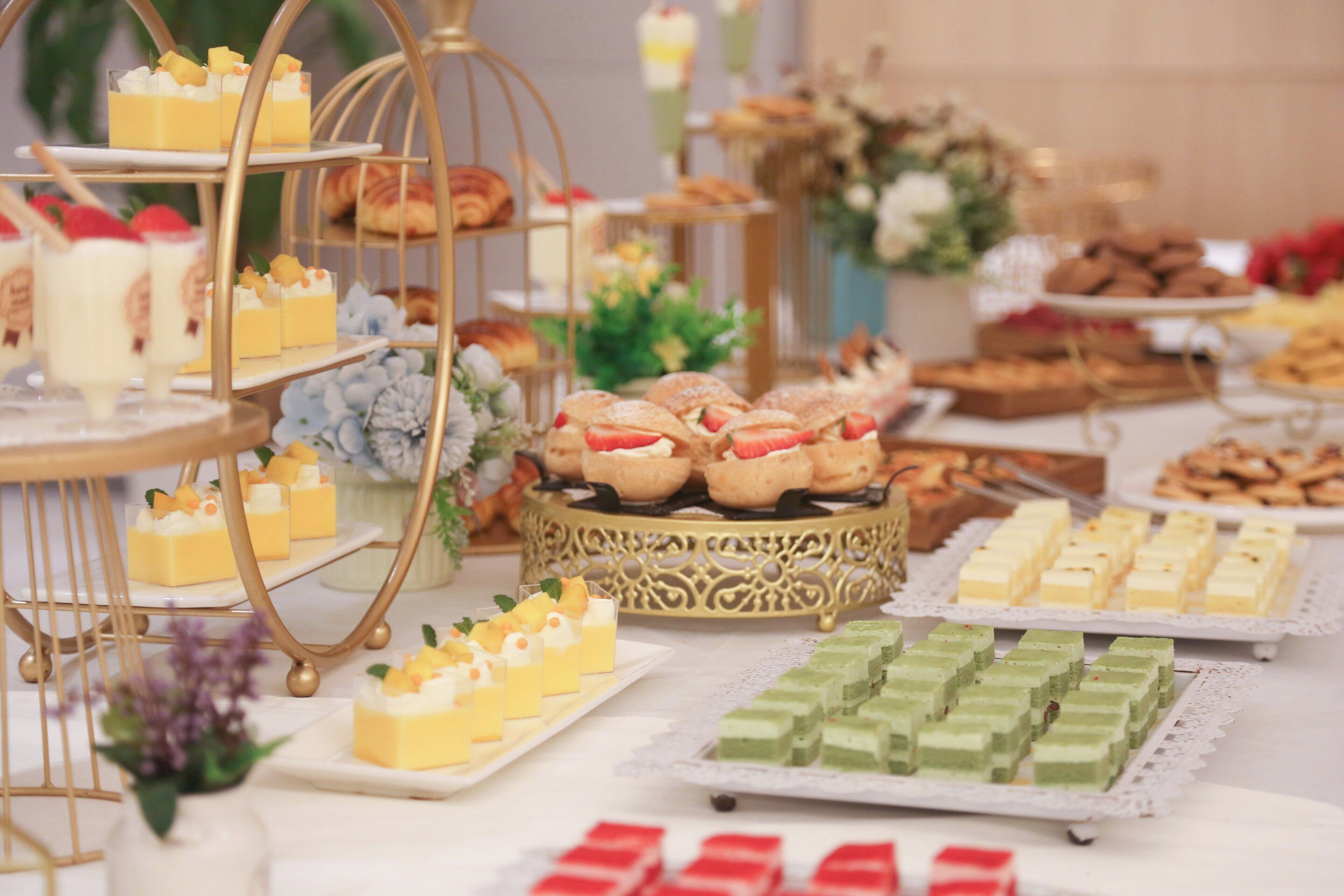 Une grande variété de desserts et de pâtisseries étaient exposés, notamment des gâteaux, des cupcakes et d’autres douceurs, présentés sur différents présentoirs et plateaux.