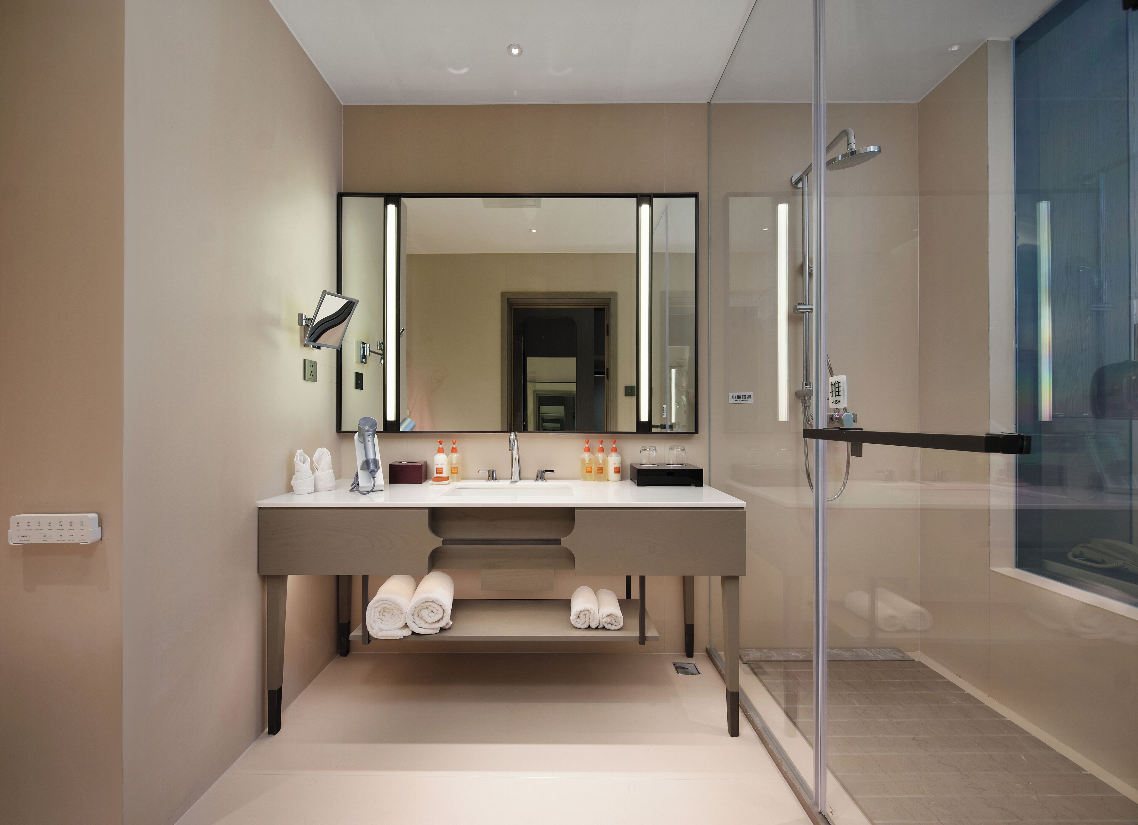 A modern bathroom with a large mirror, dual sinks, and a glass shower enclosure.
