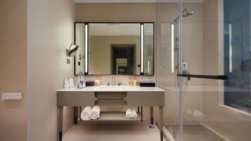 A modern bathroom with a large mirror, dual sinks, and a glass shower enclosure.