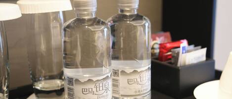 Two bottles of water labeled "Bateau" on a table with a black surface, a white cup, and a black box with items.