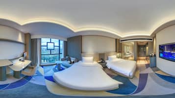 A modern hotel room with a large bed, a desk, a sofa, and a TV.