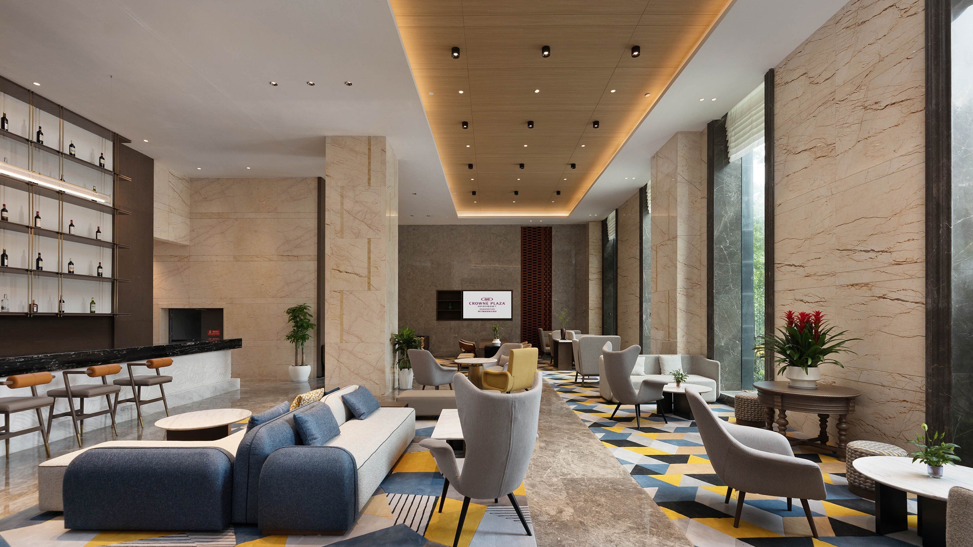 A modern lobby with a seating area, a wine display, and a large screen.