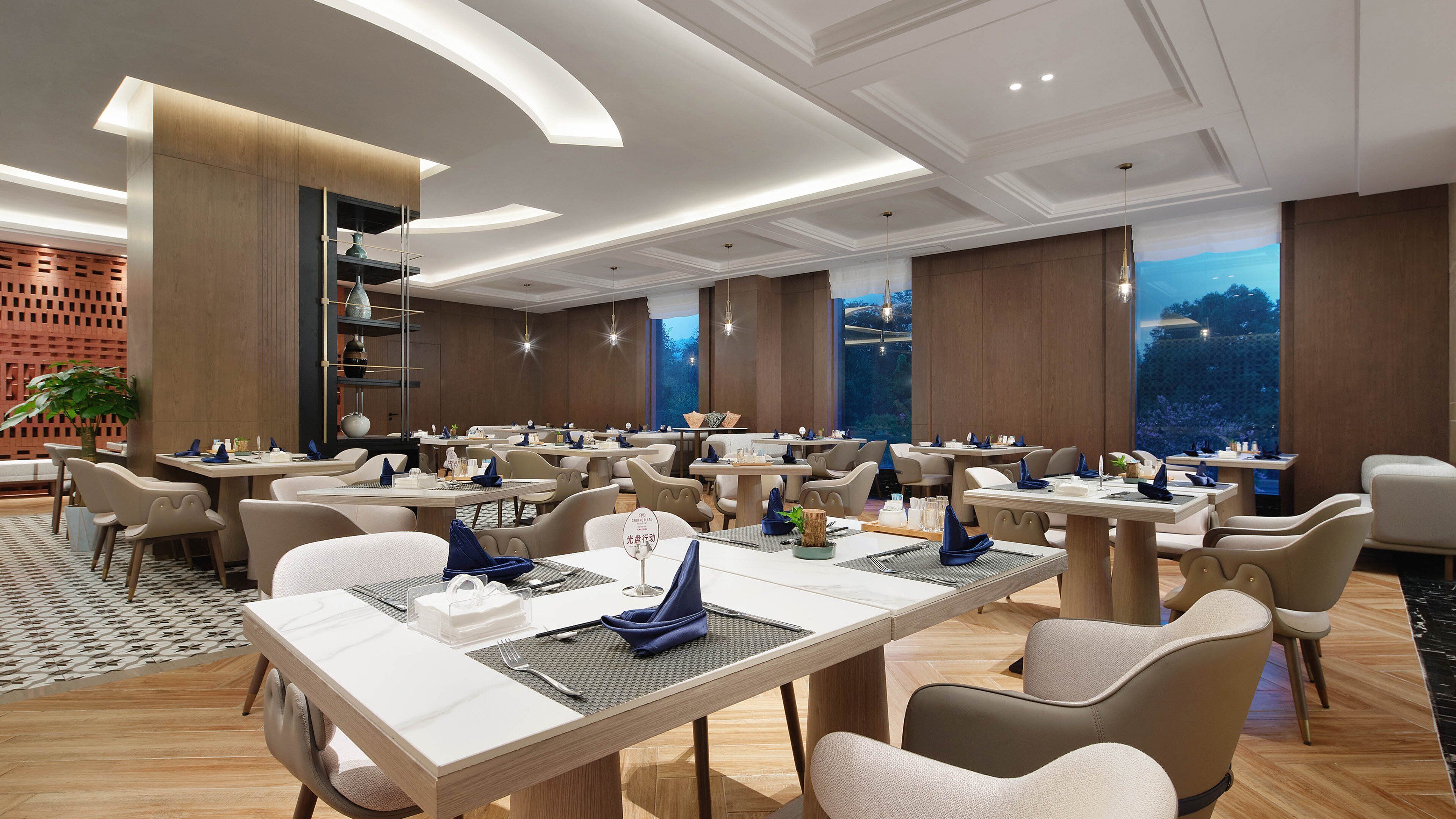 Un restaurant moderne doté de nombreuses tables et chaises, d’un plancher en bois et d’une grande fenêtre offrant une vue panoramique.