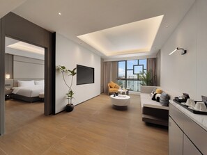 A modern hotel room with a large bed, a sofa, a coffee table, and a TV mounted on the wall. - Crowne Plaza Dujiangyan by IHG (Chengdu)