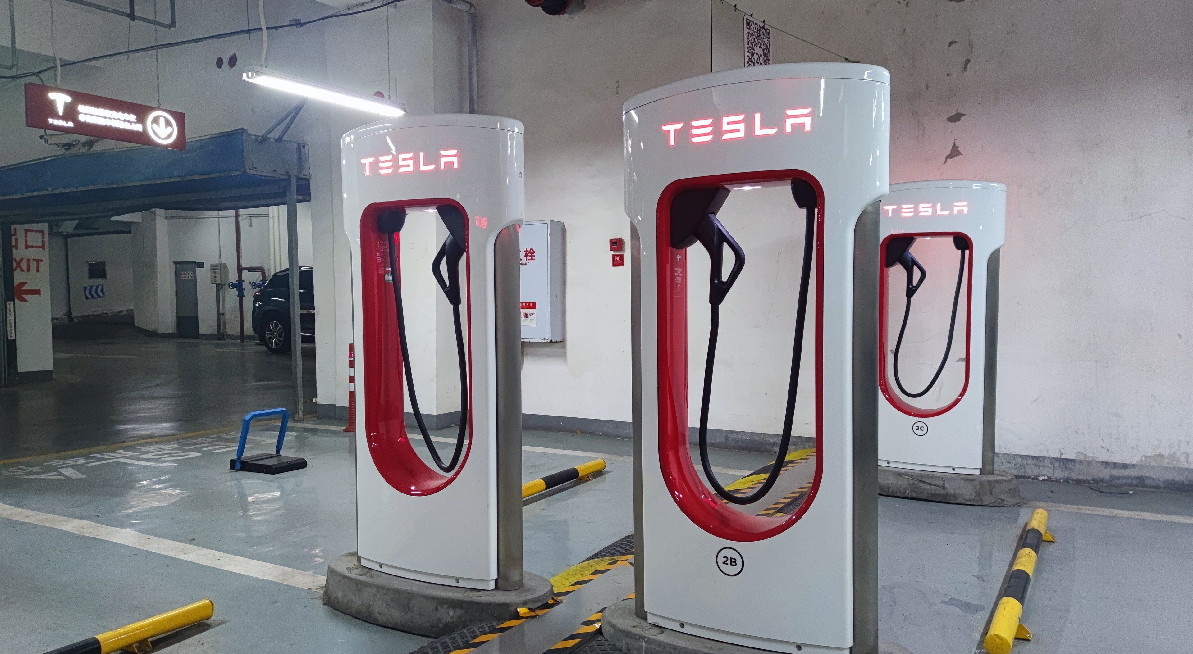 Drei Tesla-Ladesäulen für Elektrofahrzeuge in einer Parkgarage.