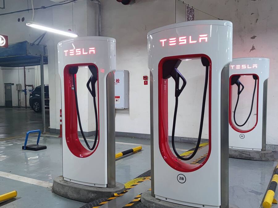 Drei Tesla-Ladesäulen für Elektrofahrzeuge in einer Parkgarage.