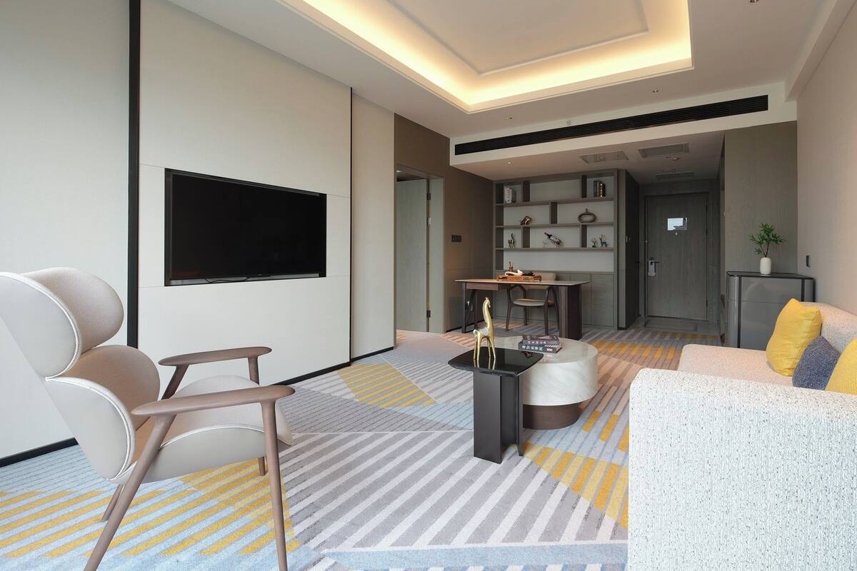 Una sala de estar moderna con un televisor de pantalla plana, un sofá, una mesa de centro y un comedor con sillas y una mesa.